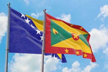 Grenada and Bosnia Herzegovina flags waving in the wind against white cloudy blue sky together. Diplomacy concept, international relations.