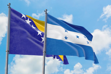 Honduras and Bosnia Herzegovina flags waving in the wind against white cloudy blue sky together. Diplomacy concept, international relations.