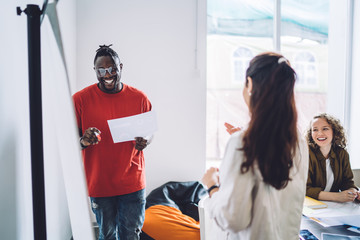 Positive multiracial business partners sharing fun ideas during meeting in contemporary conference room