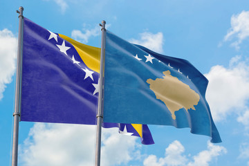 Kosovo and Bosnia Herzegovina flags waving in the wind against white cloudy blue sky together. Diplomacy concept, international relations.
