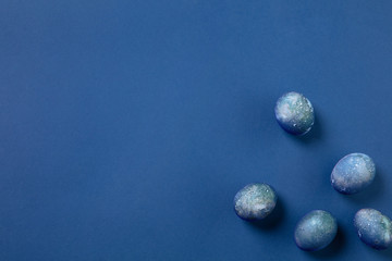 Egg hunt is coming. Easter traditions, space, cosmos colored eggs on blue background, top view, copyspace for ad or greetings. Concept of holidays, spring, celebrating, food and sweets, family time.