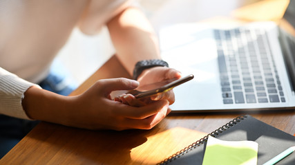 Close-up female holding her smartphone on workspace.