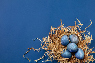 Egg hunt is coming. Easter traditions, space, cosmos colored eggs on blue background, top view, copyspace for ad or greetings. Concept of holidays, spring, celebrating, food and sweets, family time.