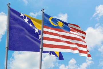 Malaysia and Bosnia Herzegovina flags waving in the wind against white cloudy blue sky together. Diplomacy concept, international relations.