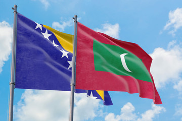 Maldives and Bosnia Herzegovina flags waving in the wind against white cloudy blue sky together. Diplomacy concept, international relations.