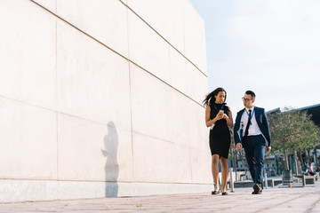 Hispanic entrepreneur showing smartphone to partner walking in street