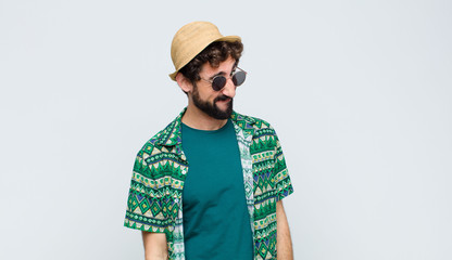 young tourist man looking happy and friendly, smiling and winking an eye at you with a positive...
