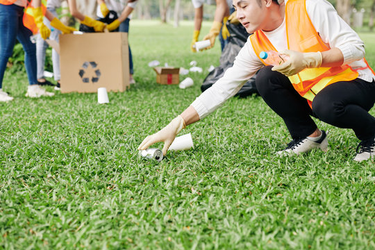 Cropped Image Of Young Vietnamese Volunteer Picking Up Plastic Bottles And Tin Cans From Ground In Park