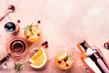 Orange Cranberry Rosemary and Vodka cocktail, copper bar tools, beige background, hard light, top...