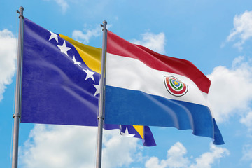 Paraguay and Bosnia Herzegovina flags waving in the wind against white cloudy blue sky together. Diplomacy concept, international relations.