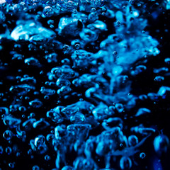 Blue wine, trendy non-classical wine drink pouring into glass on black background,  close up macro