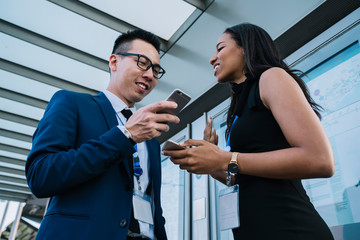 Employee standing next to colleague and communicating while using cellphone