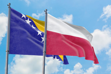 Poland and Bosnia Herzegovina flags waving in the wind against white cloudy blue sky together. Diplomacy concept, international relations.
