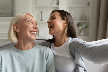 Overjoyed adult daughter and mom have fun making selfie