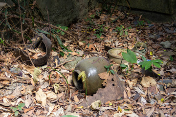 discarded and broken pots vases jars ceramic rusted metal covered in leaves on ground