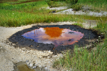 Active mud (clay and bitumen) volcano on the outskirts of the village Starunja in Carpathian. Spills of crude oil on the soil surface. Crater of the mud volcano.