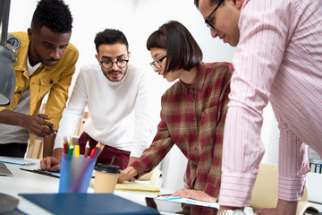 International group of young business people working and communicating standing near office desk.