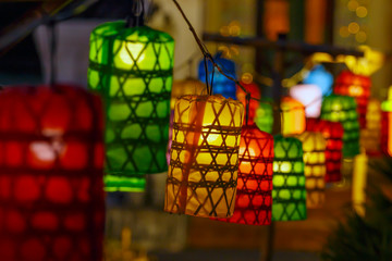 Asian colored paper lanterns with wicker pattern, backlit in the evening.
