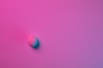 Egg hunt is coming. Easter traditions, pink-blue colored eggs on pink background, neon light, top view, copyspace for ad. Concept of holidays, spring, celebrating, food and sweets, family time.