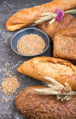 Different kinds of fresh baked bread on a black concrete background. side view.