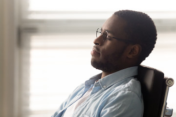 African worker resting seated on ergonomic office chair at workplace