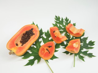 fresh red ripe papaya (pawpaw) slices on green leaves and white background.