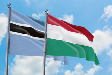 Hungary and Botswana flags waving in the wind against white cloudy blue sky together. Diplomacy concept, international relations.