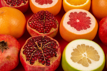 Grapefruit, orange, pomegranate, citrus sweetie on red background.