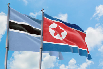 North Korea and Botswana flags waving in the wind against white cloudy blue sky together. Diplomacy concept, international relations.