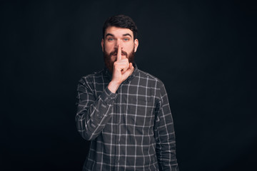 It's a secret, don't tell to anybody. Handsome bearded guy is making shut up gesture.
