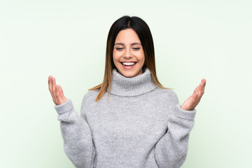 Woman wearing a sweater over isolated green background laughing