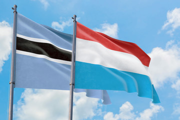 Luxembourg and Botswana flags waving in the wind against white cloudy blue sky together. Diplomacy concept, international relations.