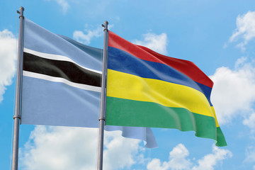 Mauritius and Botswana flags waving in the wind against white cloudy blue sky together. Diplomacy concept, international relations.