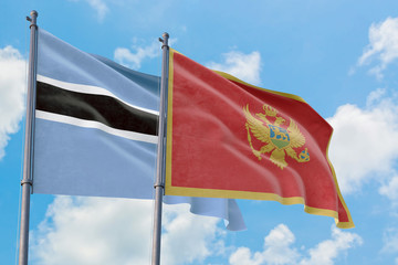 Montenegro and Botswana flags waving in the wind against white cloudy blue sky together. Diplomacy concept, international relations.