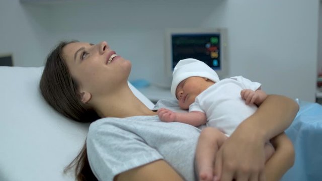 Happy family. Newborn baby sleeping in mother arms. Mom right after delivery in maternity hospital, Parturient woman holding new born child after birth labor Childbirth pregnant motherhood 4 K slow-mo