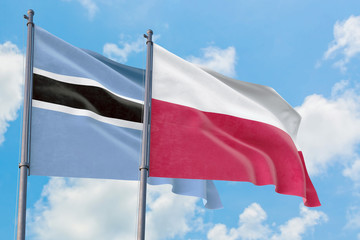 Poland and Botswana flags waving in the wind against white cloudy blue sky together. Diplomacy concept, international relations.
