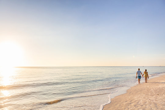 Beach relaxing vacation - travel tourists couple walking on beach at sunset landscape background. Summer holidays destination.