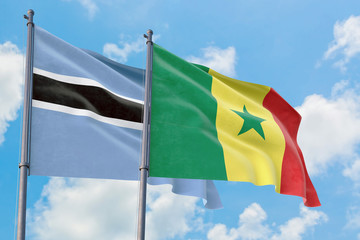 Senegal and Botswana flags waving in the wind against white cloudy blue sky together. Diplomacy concept, international relations.