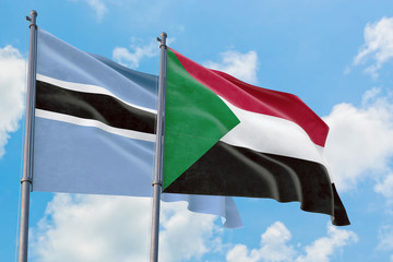 Sudan and Botswana flags waving in the wind against white cloudy blue sky together. Diplomacy concept, international relations.