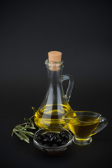Olive oil with dark olives on black background.