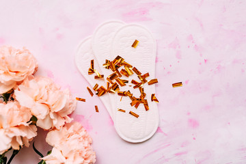 feminine hygiene products on a light background with pink flowers. flat lay of laying and flowers