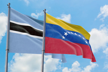 Venezuela and Botswana flags waving in the wind against white cloudy blue sky together. Diplomacy concept, international relations.