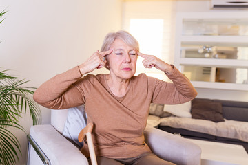 Woman suffering from stress or a headache grimacing in pain. Senior woman with migraine feeling unwell. Portrait of an attractive senior woman with a headache, feeling pain