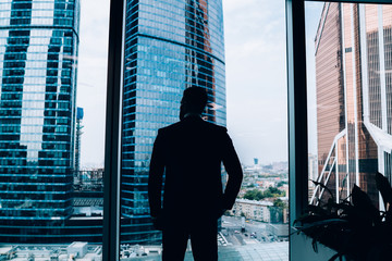 Confident male manager standing at window in office