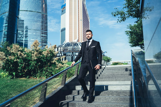 Businessman Walking Down Stairs Holding To Railing On Street