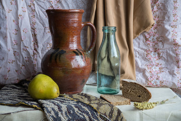 Still life with a jug, a bottle, a pear and rye bread. Russian style of painting