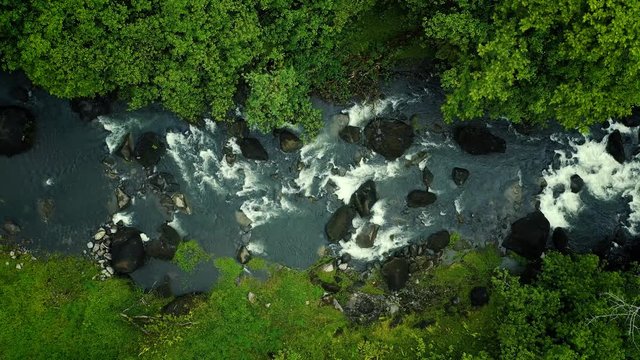 Aerial view over the river flowing between stones and vegetation of the rainforest in Papenoo. Beautiful nature landscape perfect for travel and adventure in French Polynesia - drone view