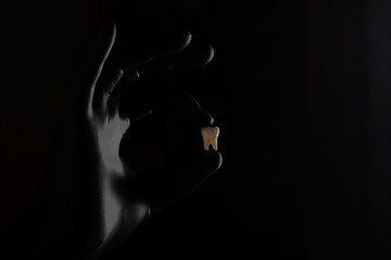  Doctor holds a man’s tooth in a black glove macro photo