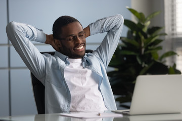 African worker put hands behind head relaxing on office chair