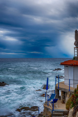 Severe weather on the Mediterranean coast in the summer, Threatening skies and white waves splashing 5 meters up a coastline with buildings that are abandoned